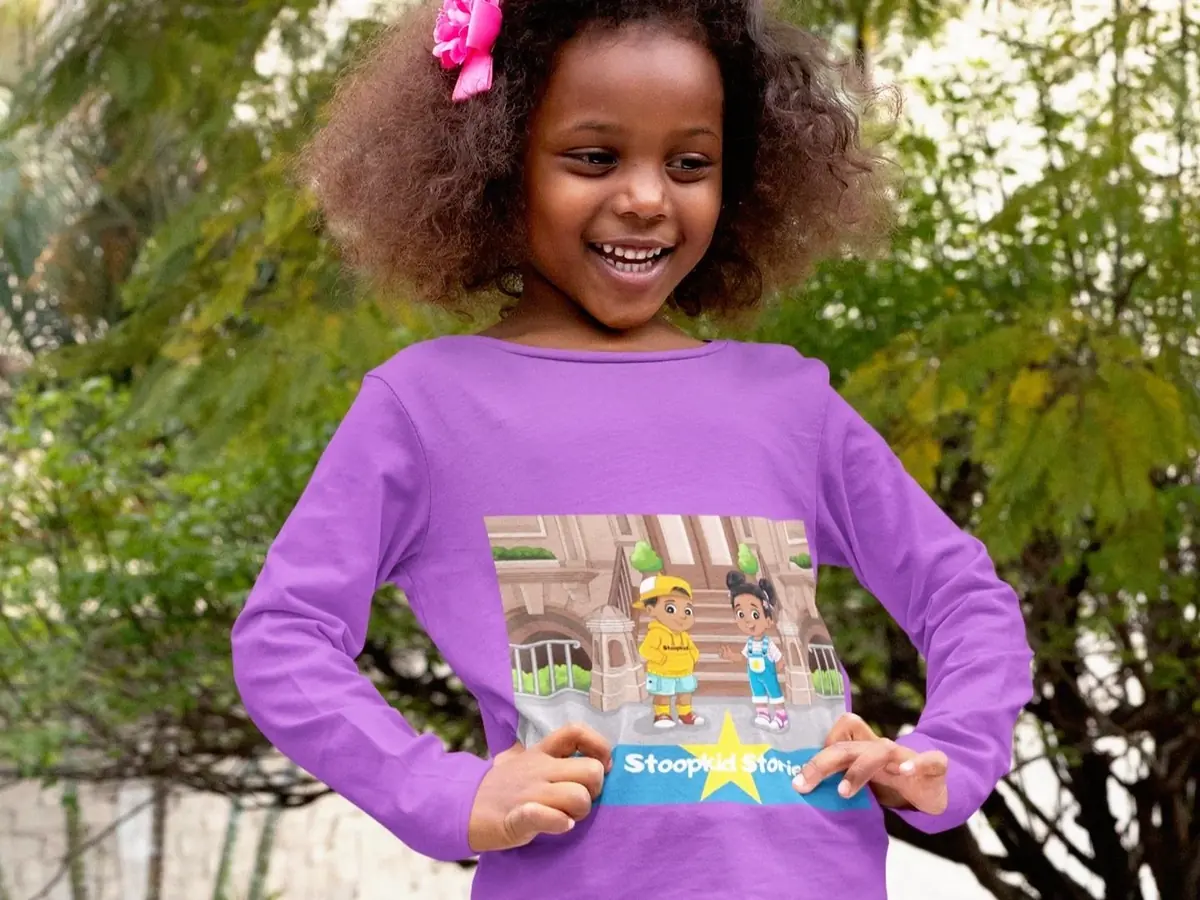 A smiling girl wearing a purple Stoopkid Stories long-sleeve tee